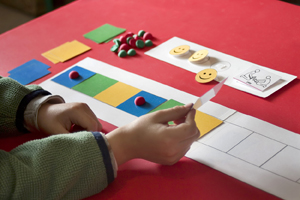 Autism therapy, Child placing colored squares in sequence on table.   Source: 85039_1_Thinkstock_105088879