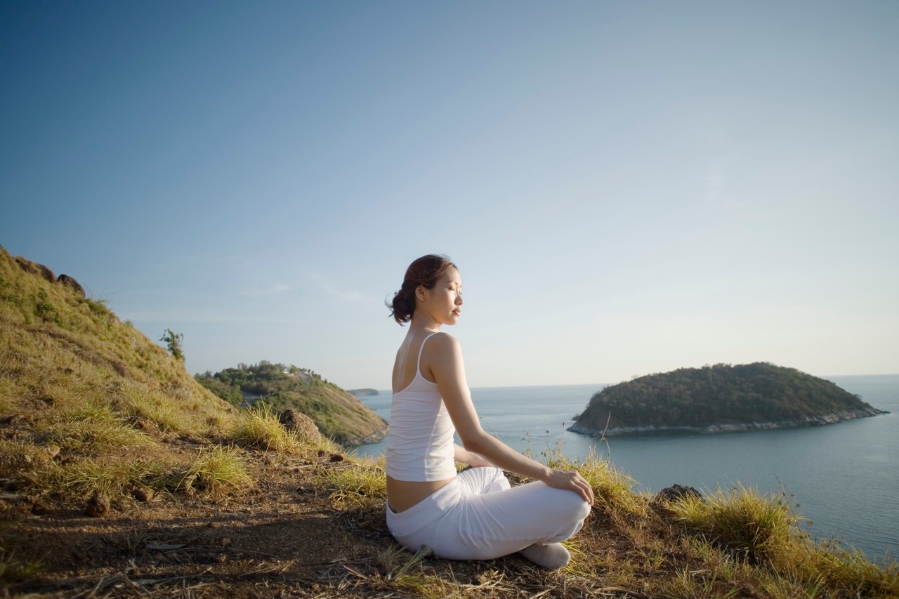 Thailand --- Young Woman Meditating on a Hill --- Image by © Ken Seet/Corbis