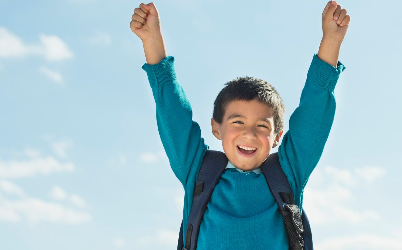 Boy (6-7) wearing backpack punching air --- Image by © Tetra Images/Corbis