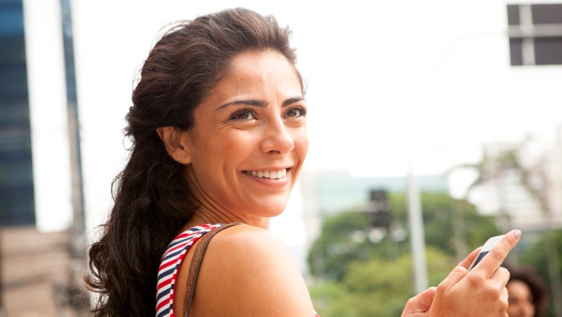 São Paulo, Brazil --- Woman smiles off camera in business district, Sao Paulo, Brazil --- Image by © JAG Images/Corbis