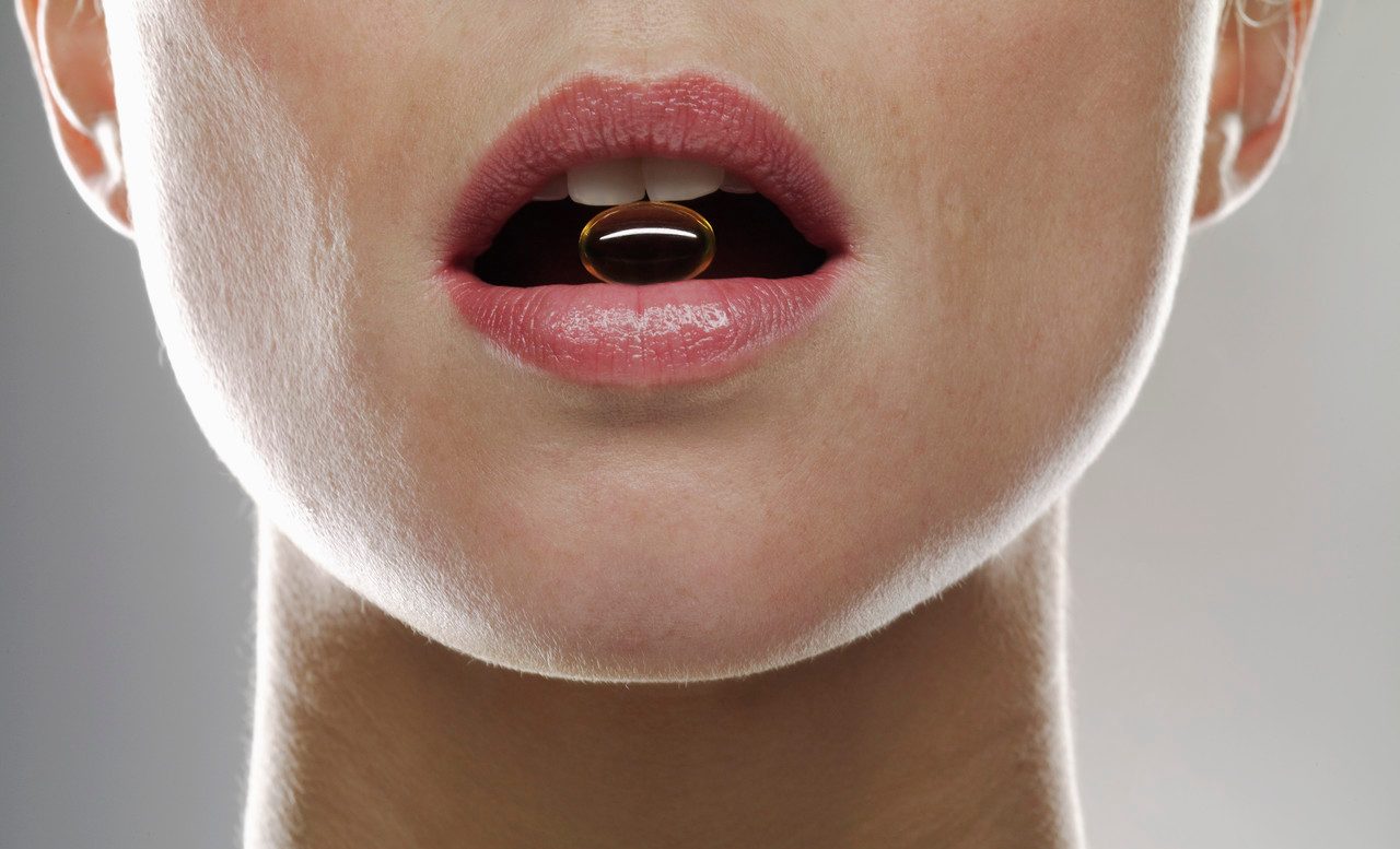 Woman with Vitamin in Mouth --- Image by © Michael Haegele/Corbis