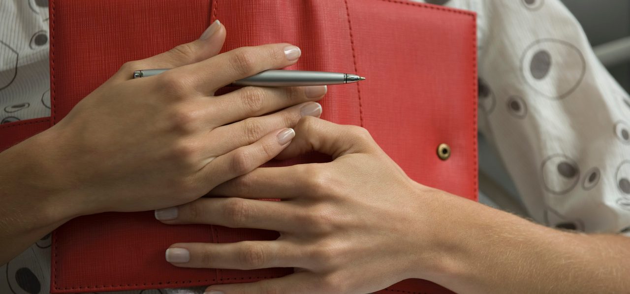 Woman holding diary on chest, cropped view --- Image by © Odilon Dimier/PhotoAlto/Corbis