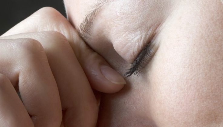 A Woman Squeezing the Bridge of Her Nose --- Image by © Vladimir Godnik/fstop/Corbis