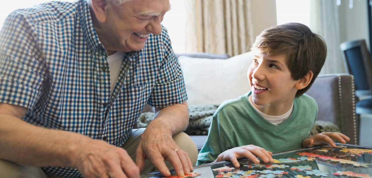 07 Feb 2014 --- Smiling grandfather and grandson solving puzzle at home --- Image by © Hero Images/Corbis