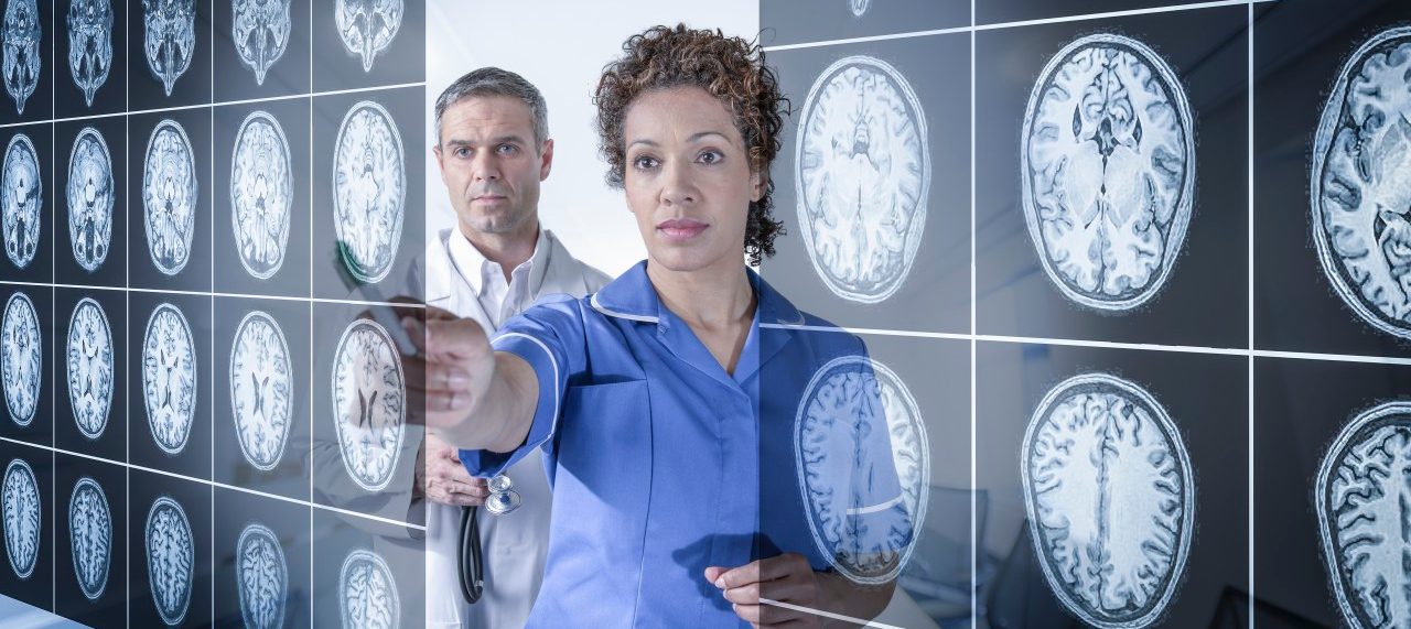 Doctor and nurse working with MRI brain scans seen through interactive display --- Image by © Monty Rakusen/Corbis