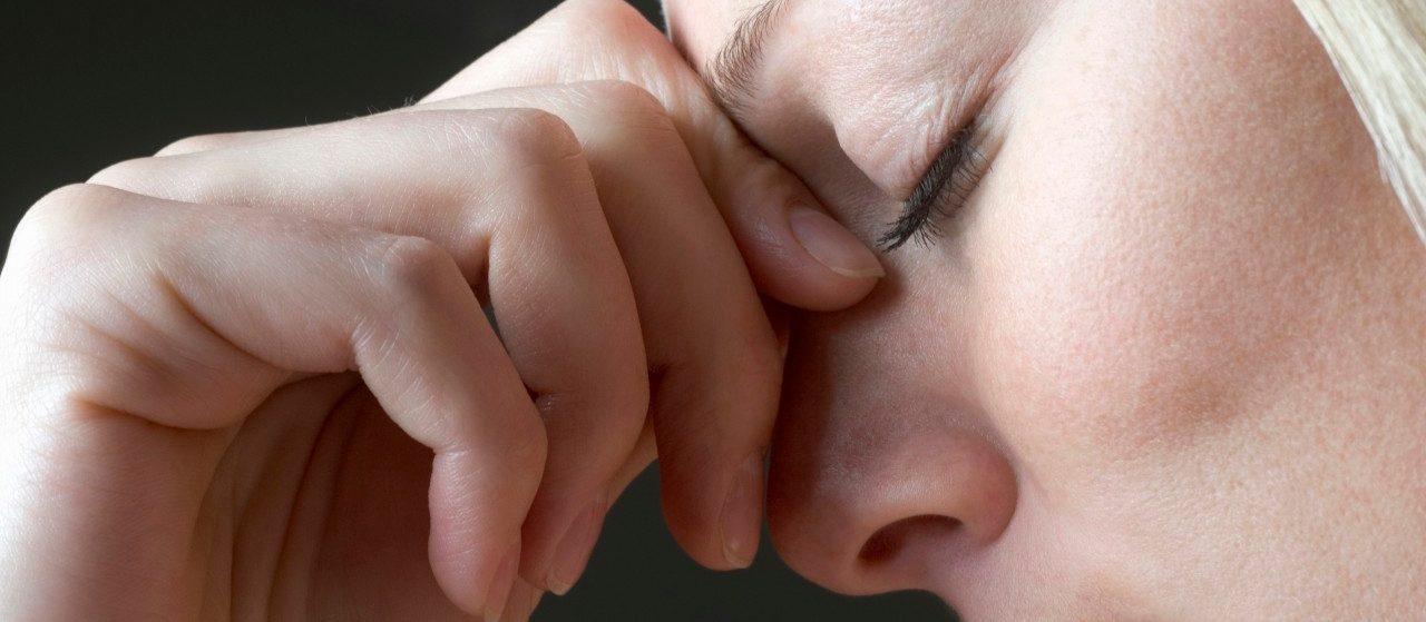 A Woman Squeezing the Bridge of Her Nose --- Image by © Vladimir Godnik/fstop/Corbis