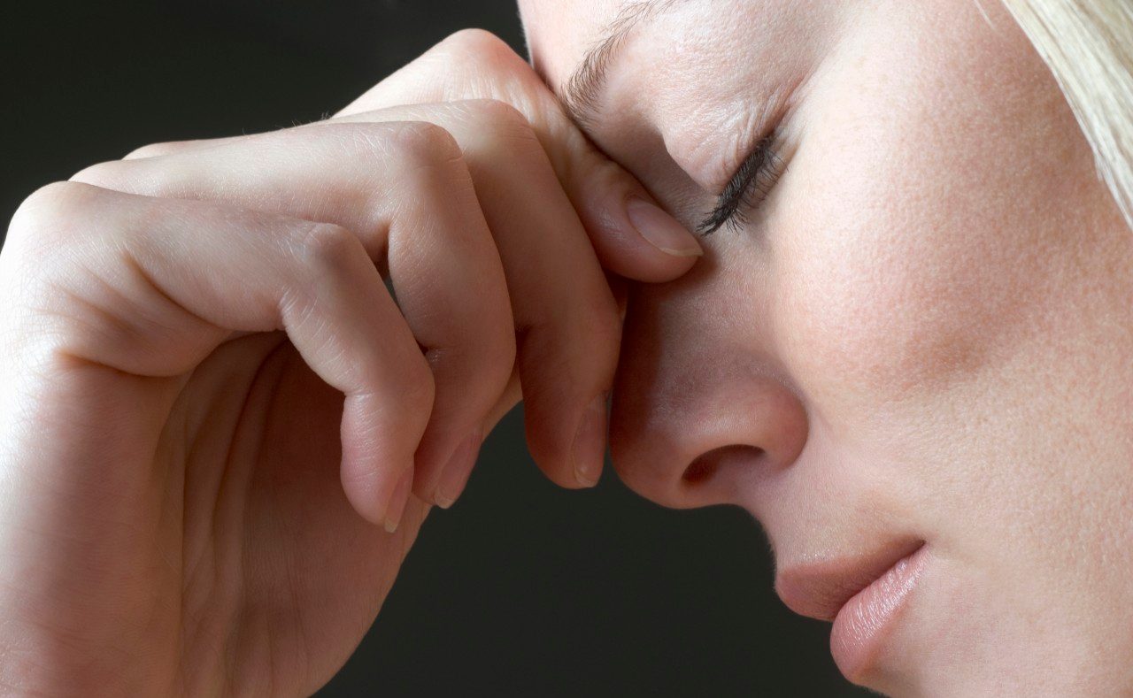 A Woman Squeezing the Bridge of Her Nose --- Image by © Vladimir Godnik/fstop/Corbis