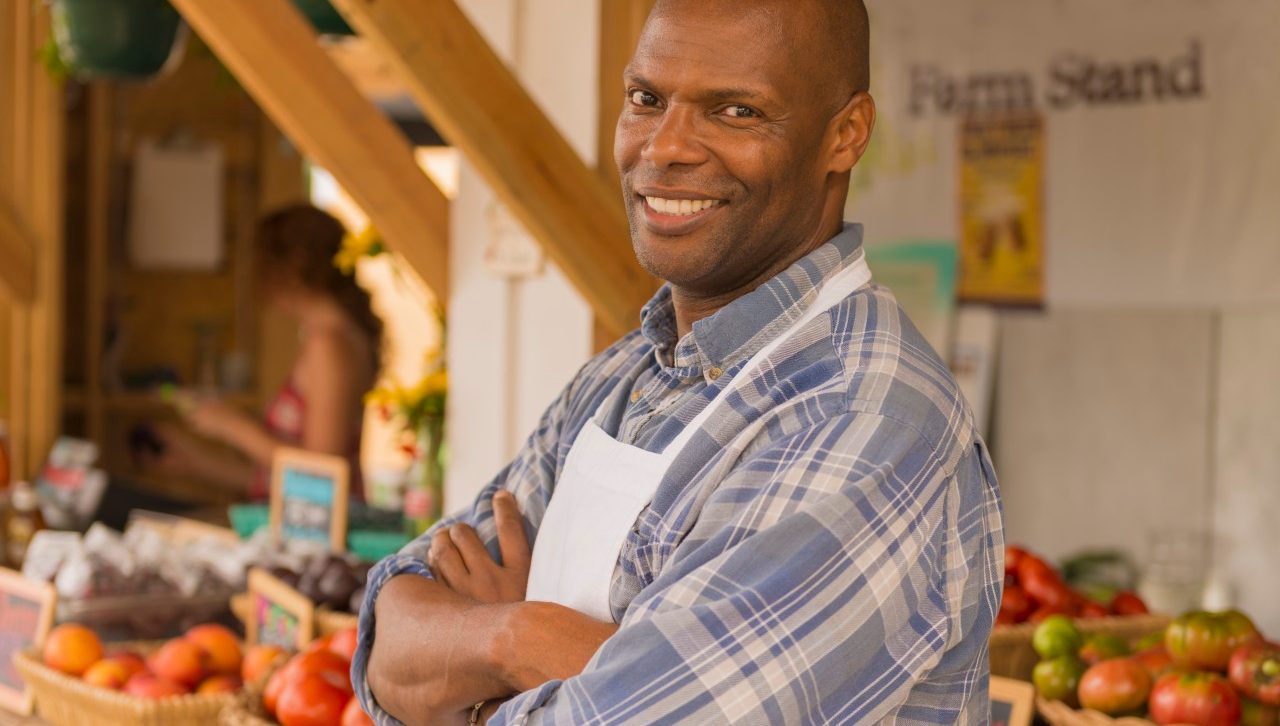 07 Aug 2014, Virginia Beach, Virginia, USA --- African American vendor smiling at farmers market --- Image by © Mark Edward Atkinson/Tracey Lee/Blend Images/Corbis