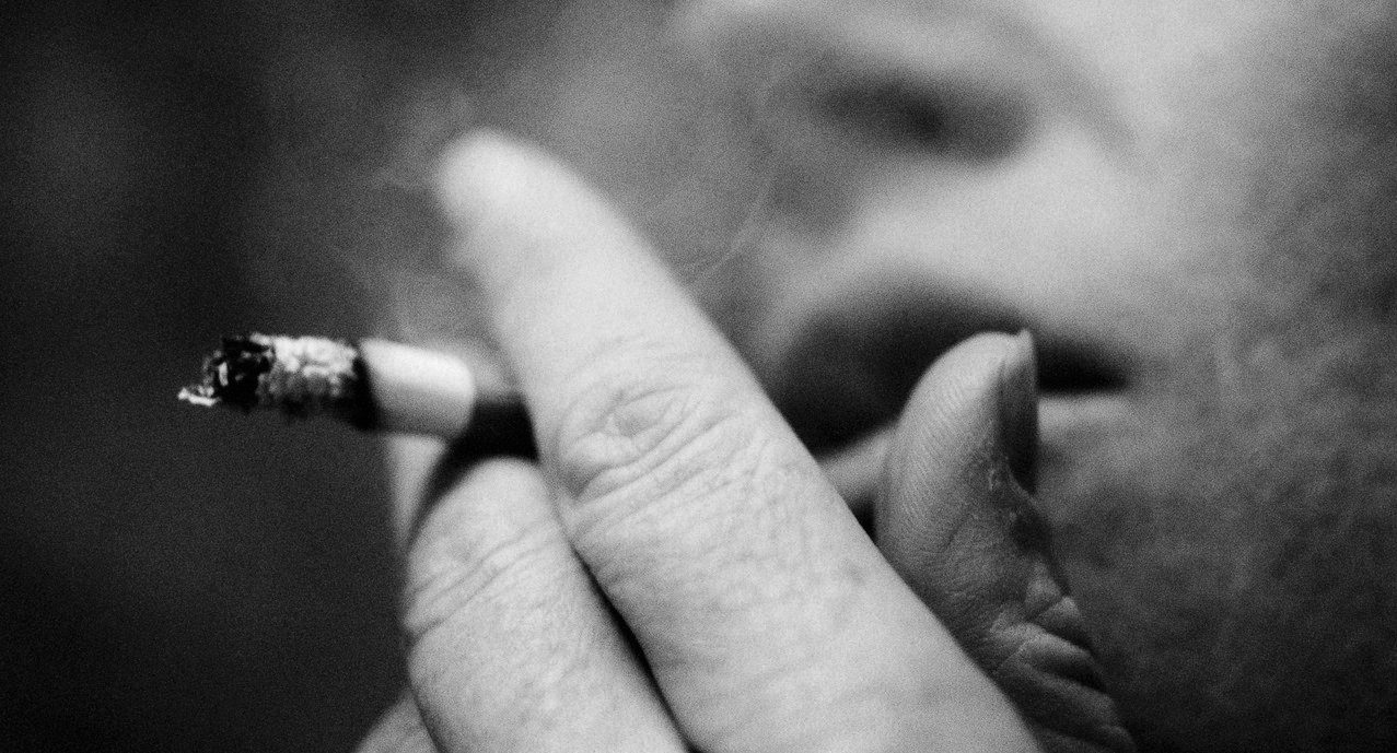 Person Smoking Cigarette, Close-up, Blurred, B&w --- Image by © Laurent Hamels/PhotoAlto/Corbis