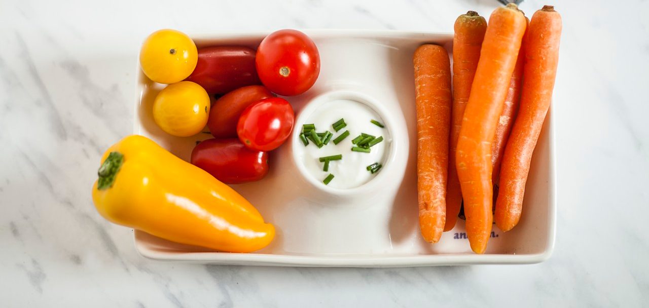 07 Nov 2014 --- Baby-sized vegetables, carrots, tomatoes, bell pepper with sour-cream-dip, toy car, studio --- Image by © Susan Brooks-Dammann/Westend61/Corbis