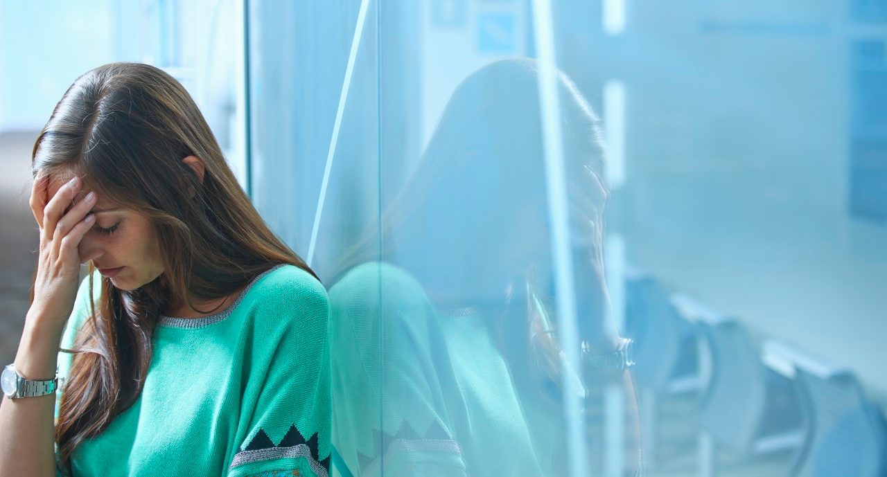 25 Apr 2014 --- Mid adult businesswoman leaning against glass wall in office with hand on face --- Image by © Ghislain & Marie David de Lossy/Corbis