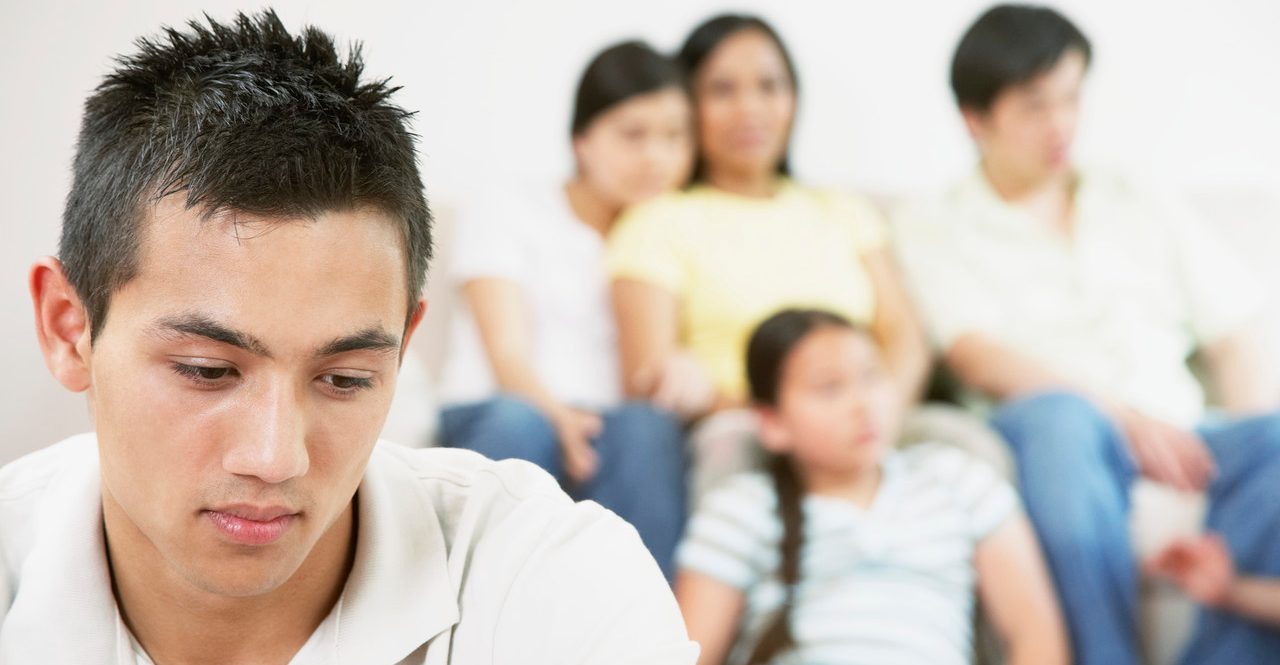 Teen boy with family in background --- Image by © Tomas Rodriguez/Corbis