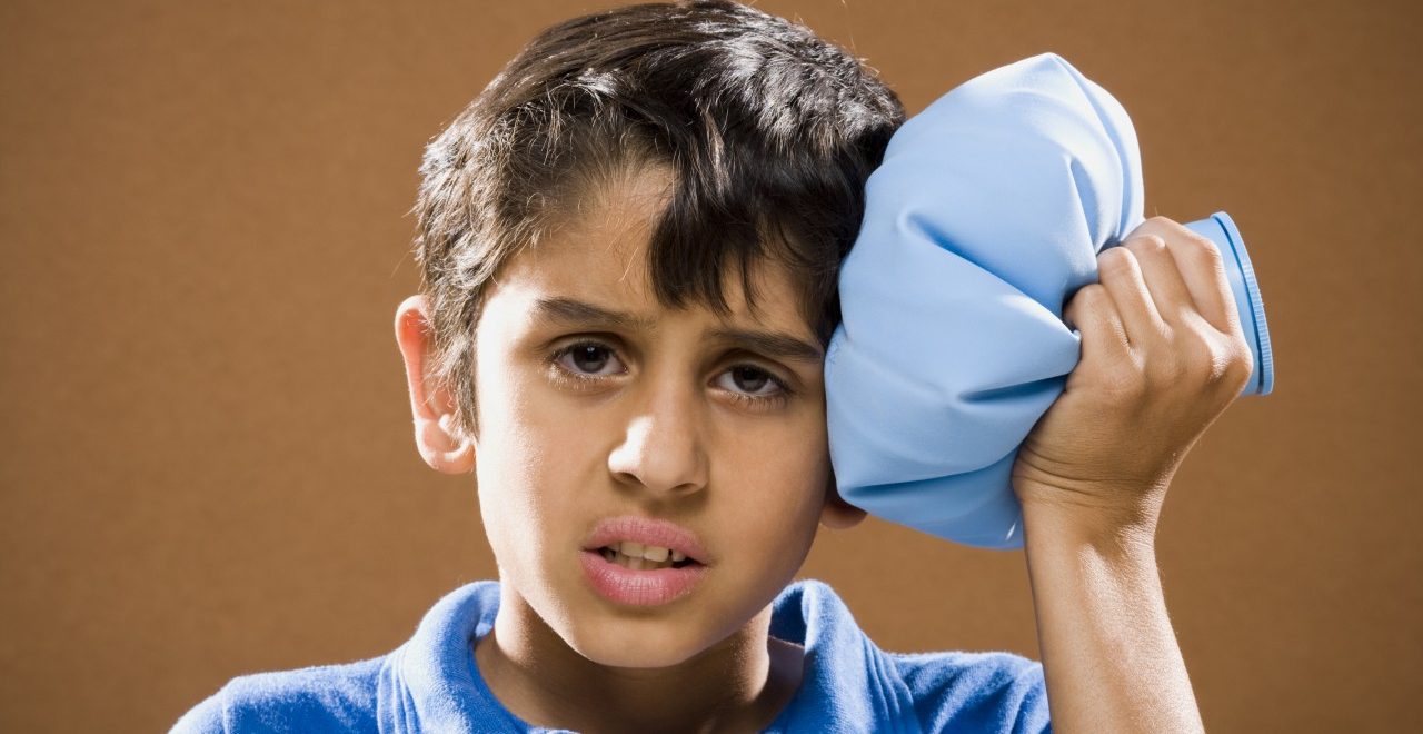 Boy holding ice pack to head --- Image by © Mike Kemp/Rubberball/Corbis