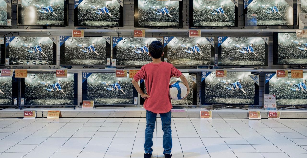 Back view of boy watching soccer in electronics store --- Image by © Hiya Images/Corbis