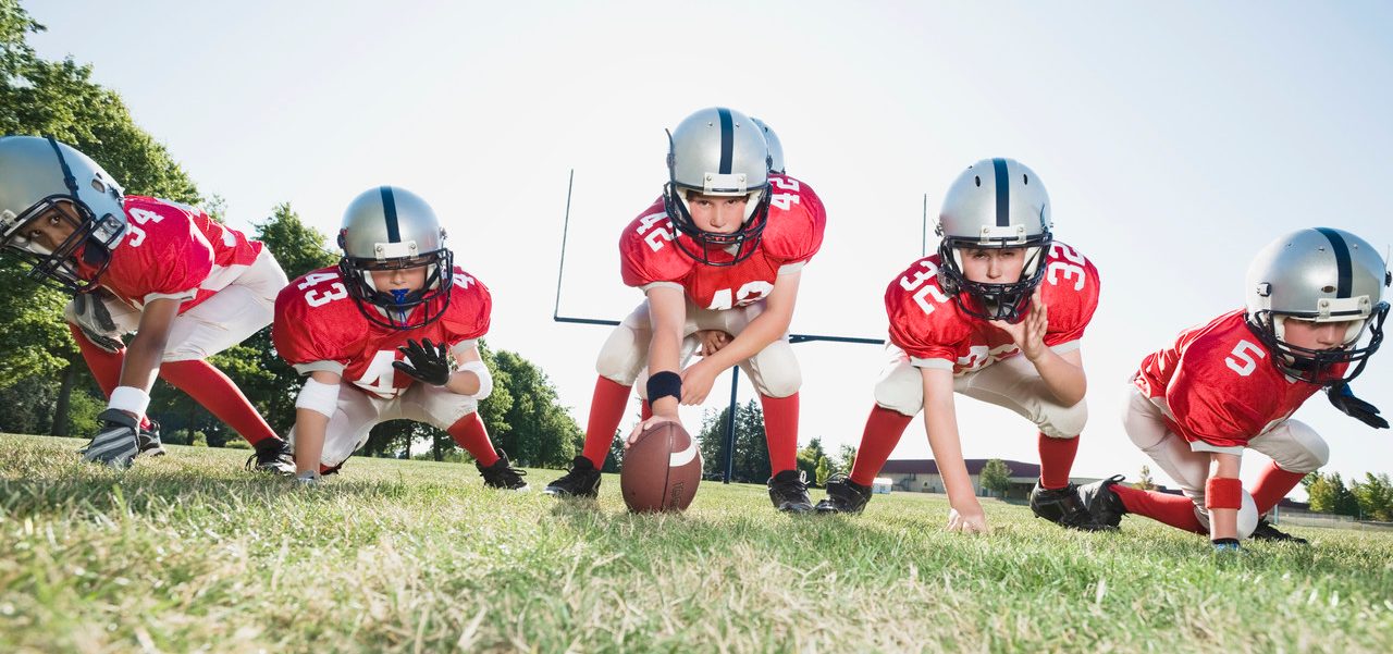 Football players at line of scrimmage ready to snap football --- Image by © Erik Isakson/Tetra Images/Corbis