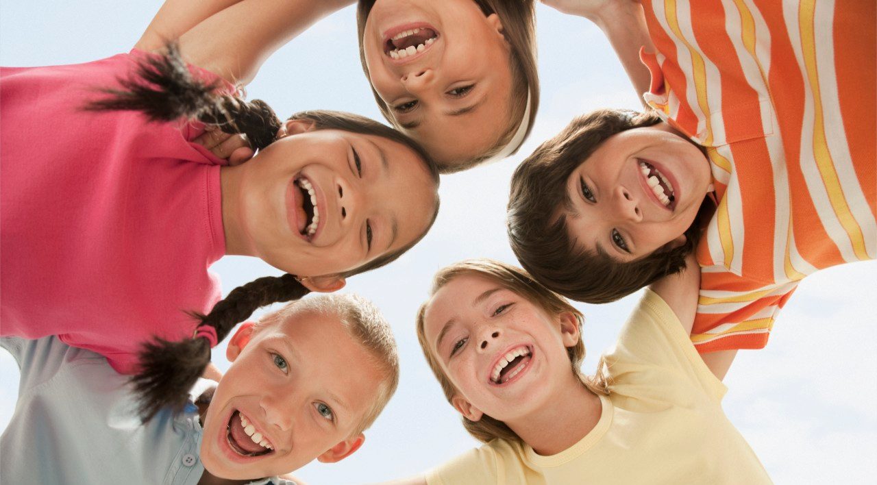 West New York, New Jersey, USA --- Smiling children huddling together --- Image by © KidStock/Blend Images/Corbis