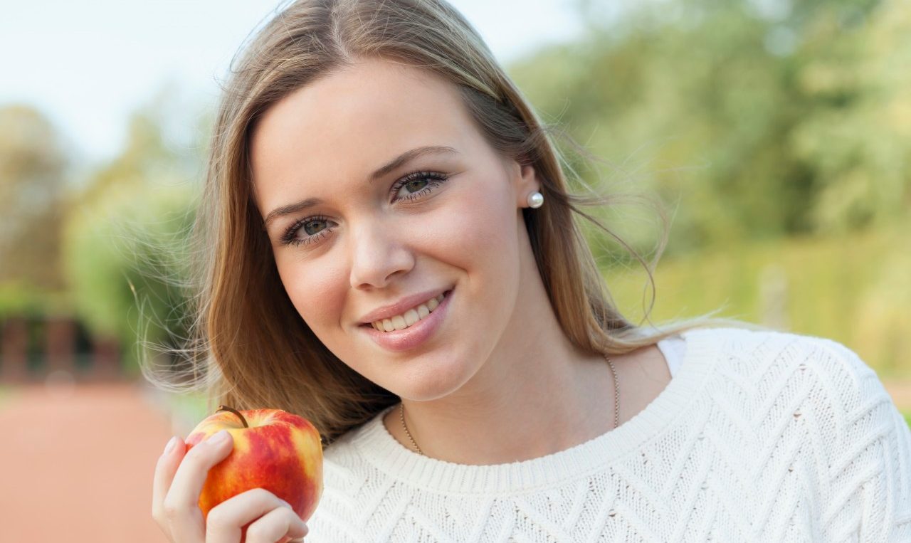 18 Oct 2014, Düsseldorf, Germany --- Portrait of smiling blond teenage girl eating an apple --- Image by © reka prod./Westend61/Corbis