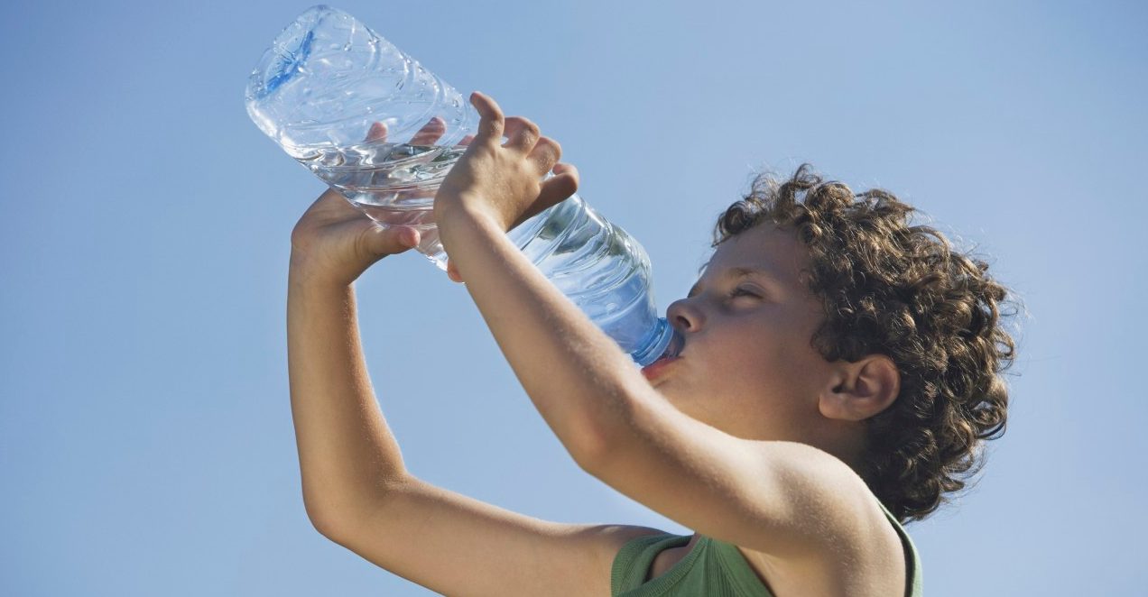 Low angle of young boy drinking water --- Image by © Steve Sparrow/cultura/Corbis