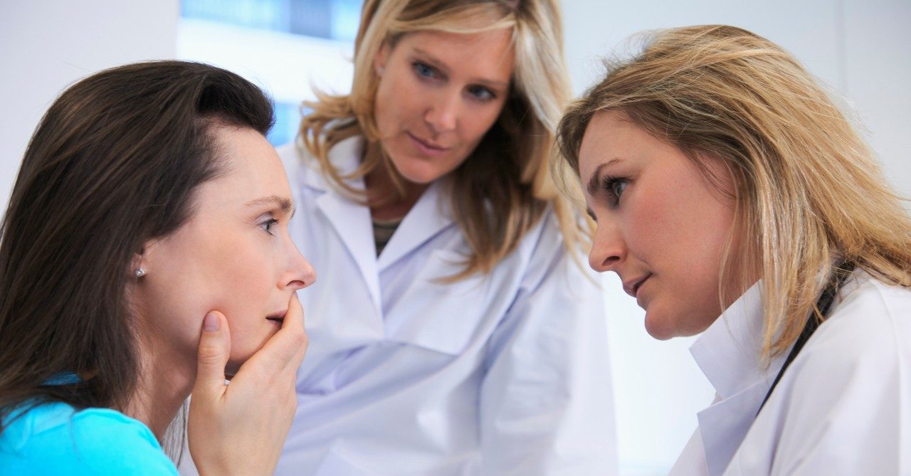 Doctors comforting female patient --- Image by © Ghislain & Marie David de Lossy/Corbis