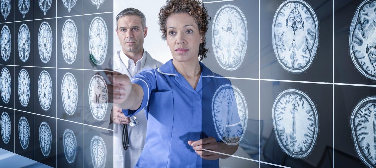 Doctor and nurse working with MRI brain scans seen through interactive display --- Image by © Monty Rakusen/Corbis