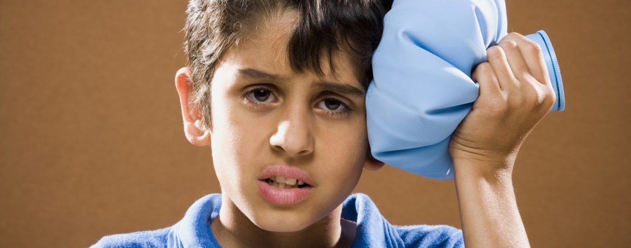 Boy holding ice pack to head --- Image by © Mike Kemp/Rubberball/Corbis