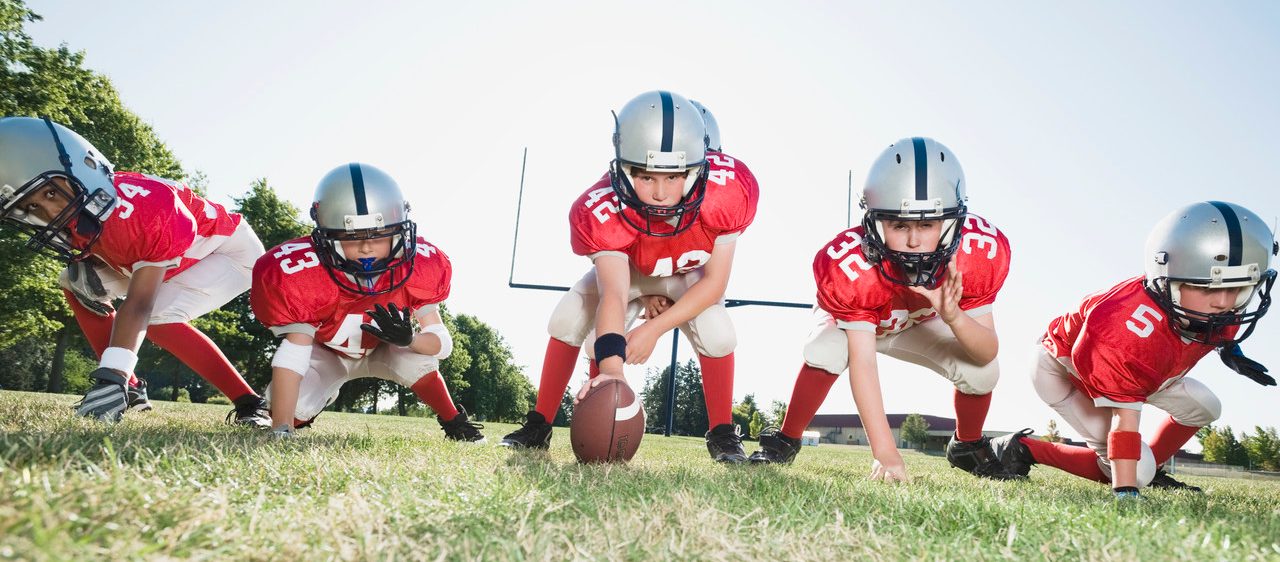 Football players at line of scrimmage ready to snap football --- Image by © Erik Isakson/Tetra Images/Corbis