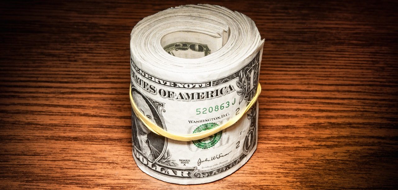 03 Jun 2014, USA --- Roll of american dollar notes wrapped in elastic band on office desk --- Image by © Stefano Oppo/Corbis