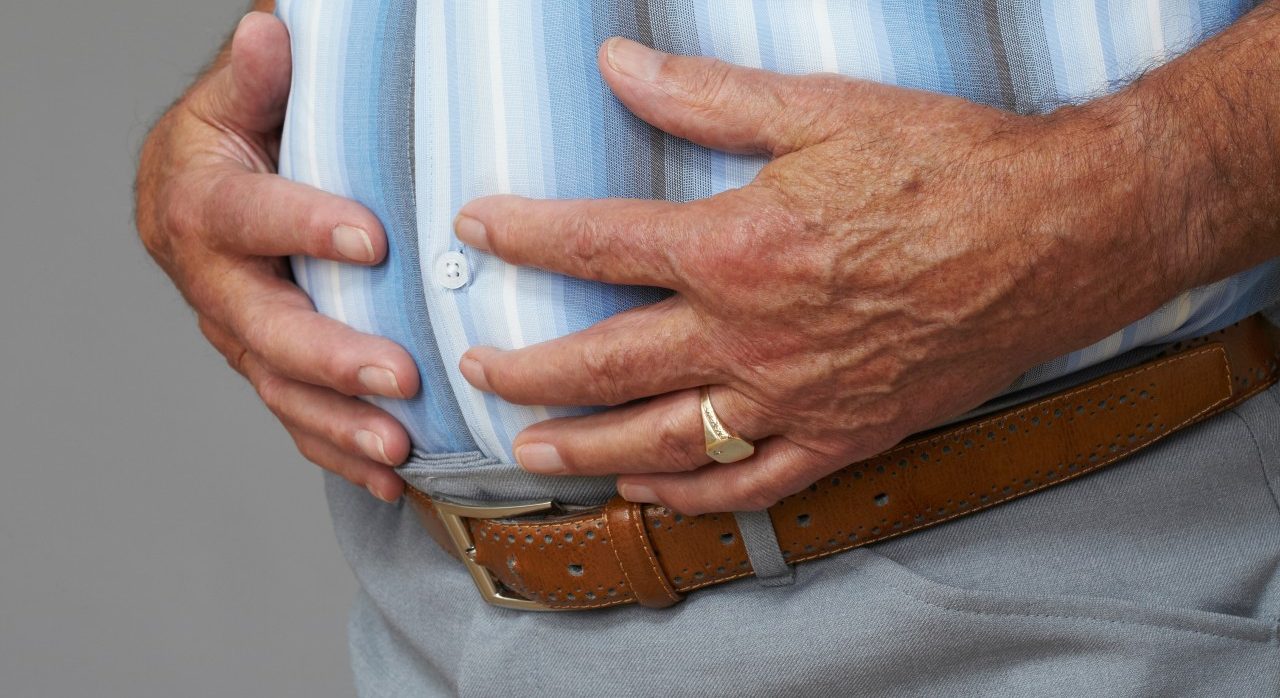 Overweight senior man touching stomach --- Image by © Nick White/Image Source/Corbis