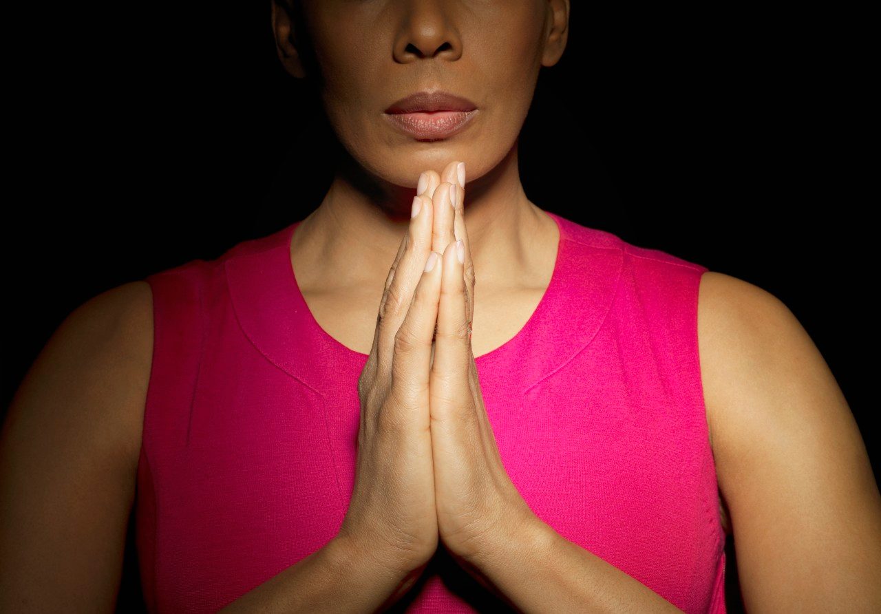 Woman with hands together --- Image by © Mark Weiss/Corbis