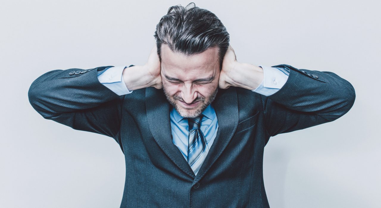 Portrait of a business man covering his ears.