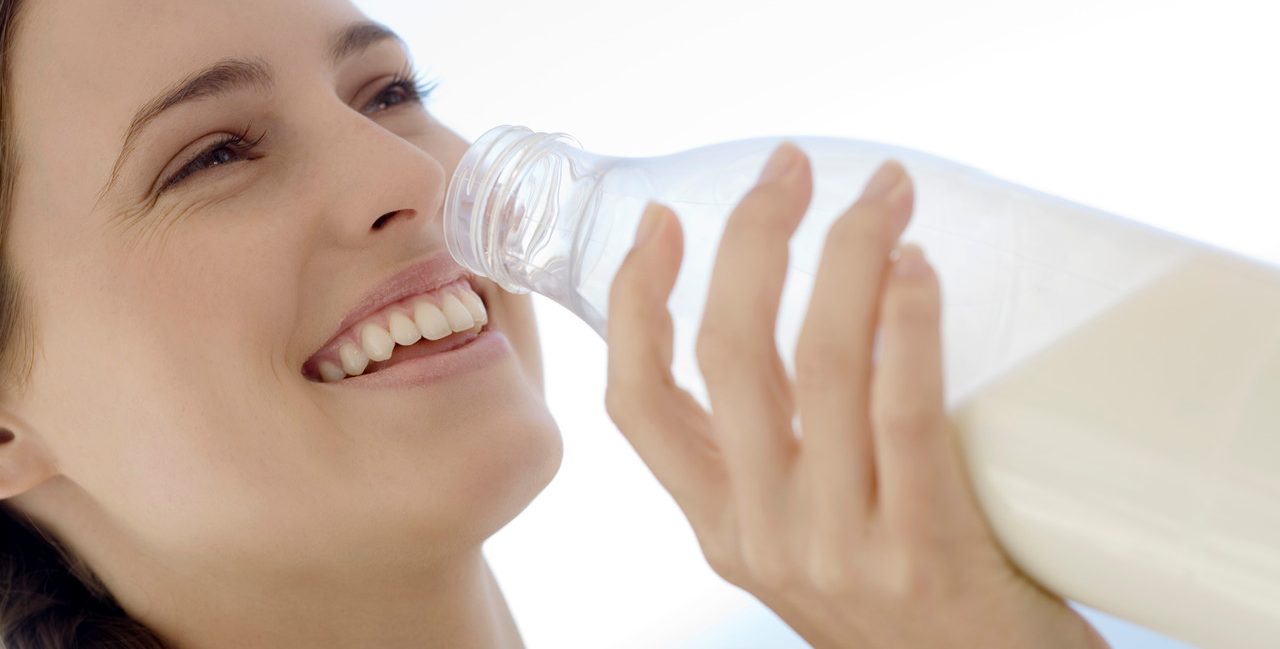 Portrait of a young woman drinking milk from the bottle, outdoors --- Image by © Elie Bernager/Onoky/Corbis