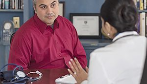 Adult hispanic male patient talking with female doctor