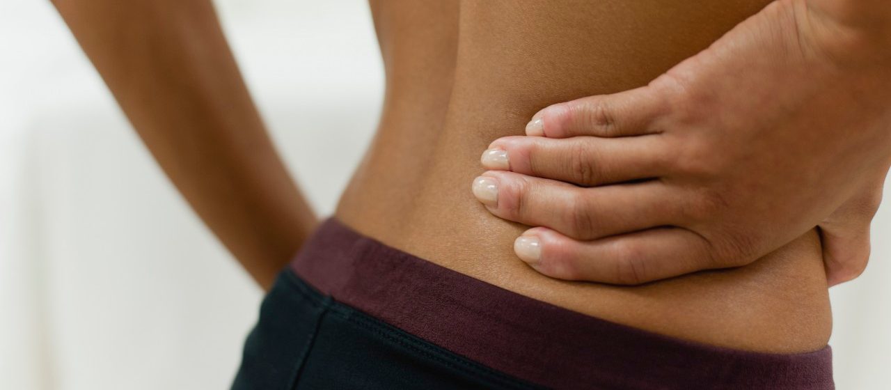 Woman with hand on lower back, mid section --- Image by © Odilon Dimier/PhotoAlto/Corbis