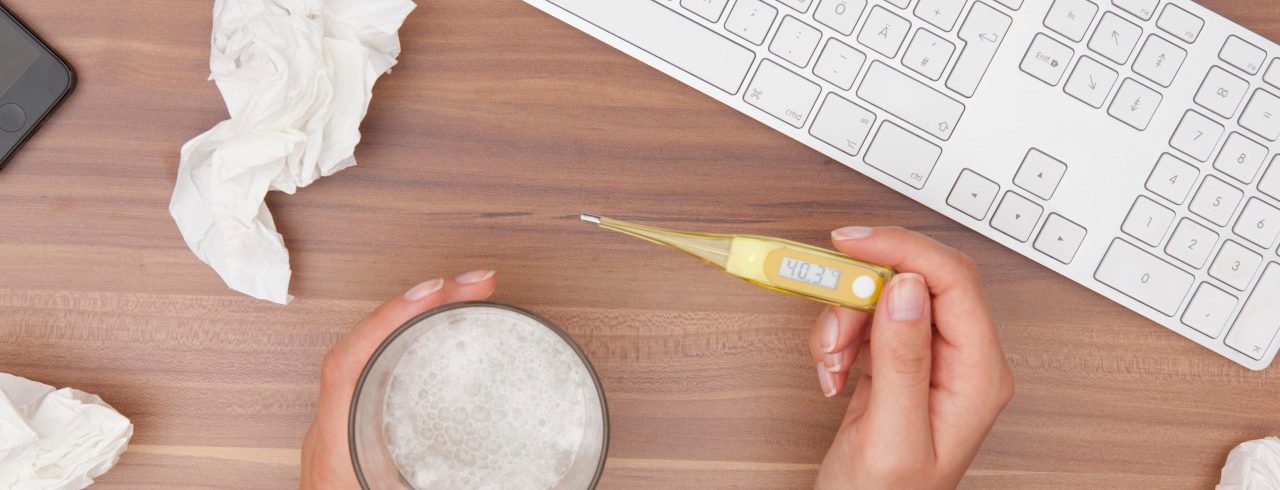 Overhead view of female hand holding thermometer in office --- Image by © Andre Schuster/Corbis