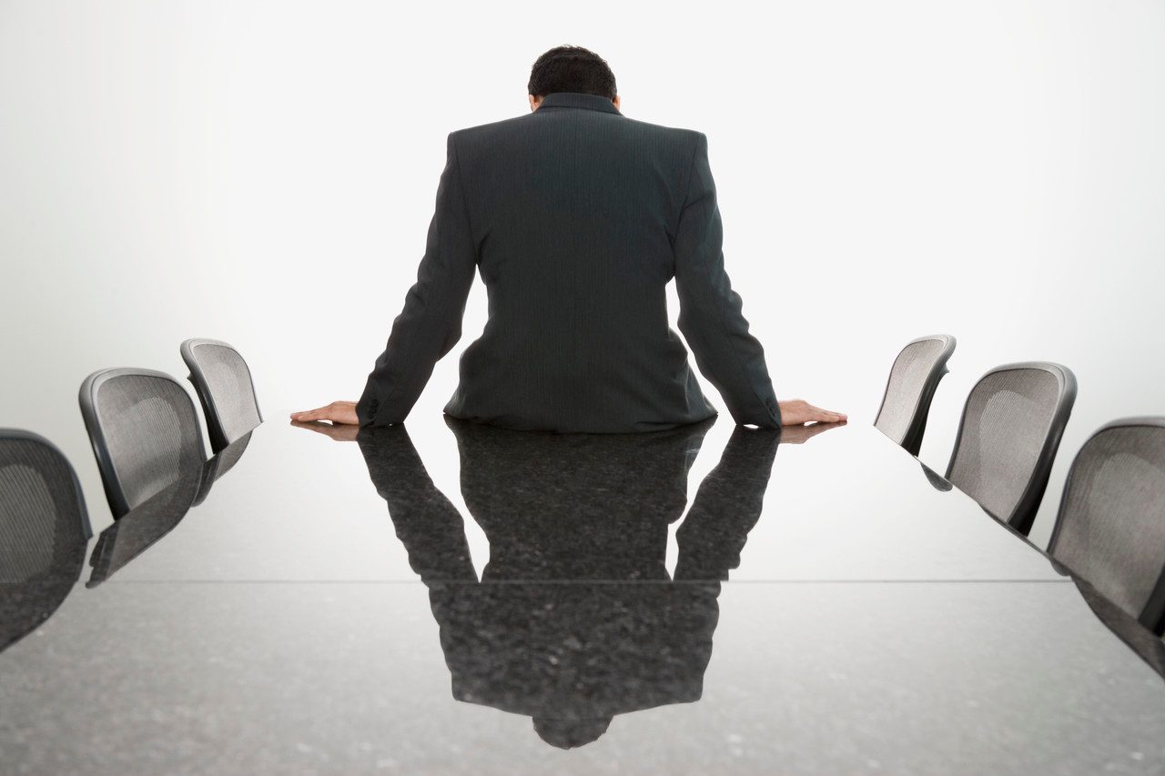 Businessman sitting slouched on edge of conference table --- Image by © Steve Hix/Somos Images/Corbis