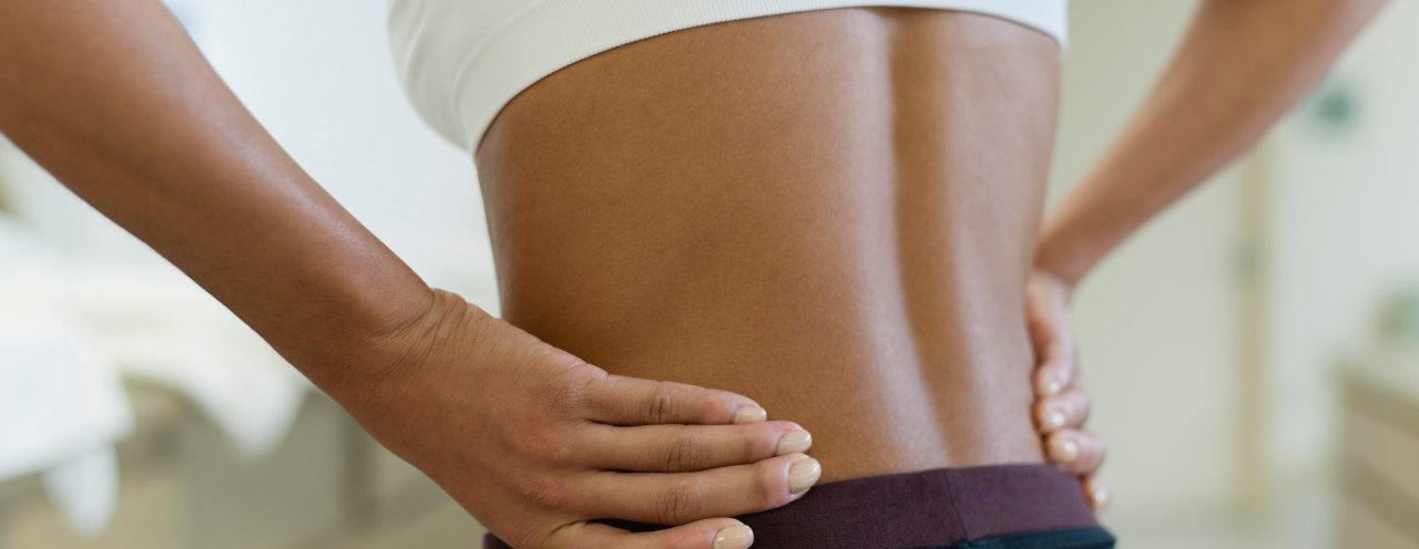 Woman with hands on lower back, mid section --- Image by © Odilon Dimier/PhotoAlto/Corbis