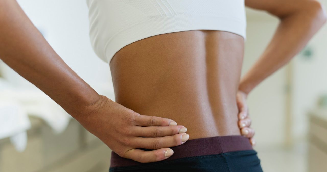 Woman with hands on lower back, mid section --- Image by © Odilon Dimier/PhotoAlto/Corbis