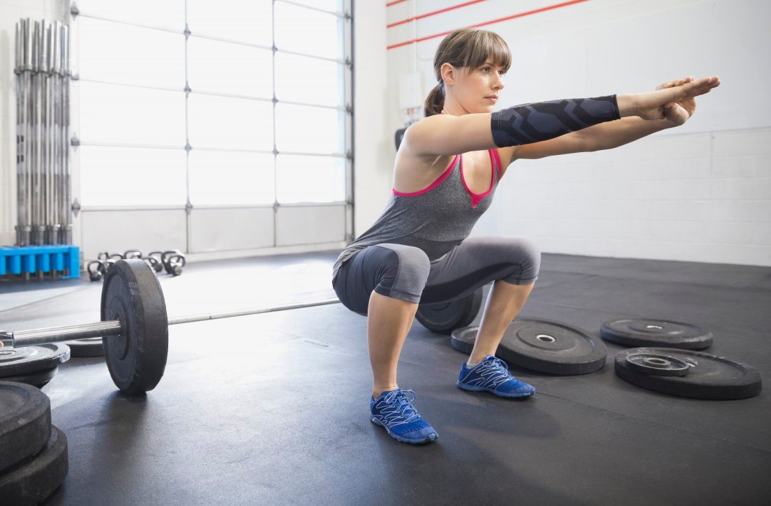 20 Nov 2013, Calgary, Alberta, Canada --- Woman warming up with squats in gym --- Image by © Hero Images/Corbis