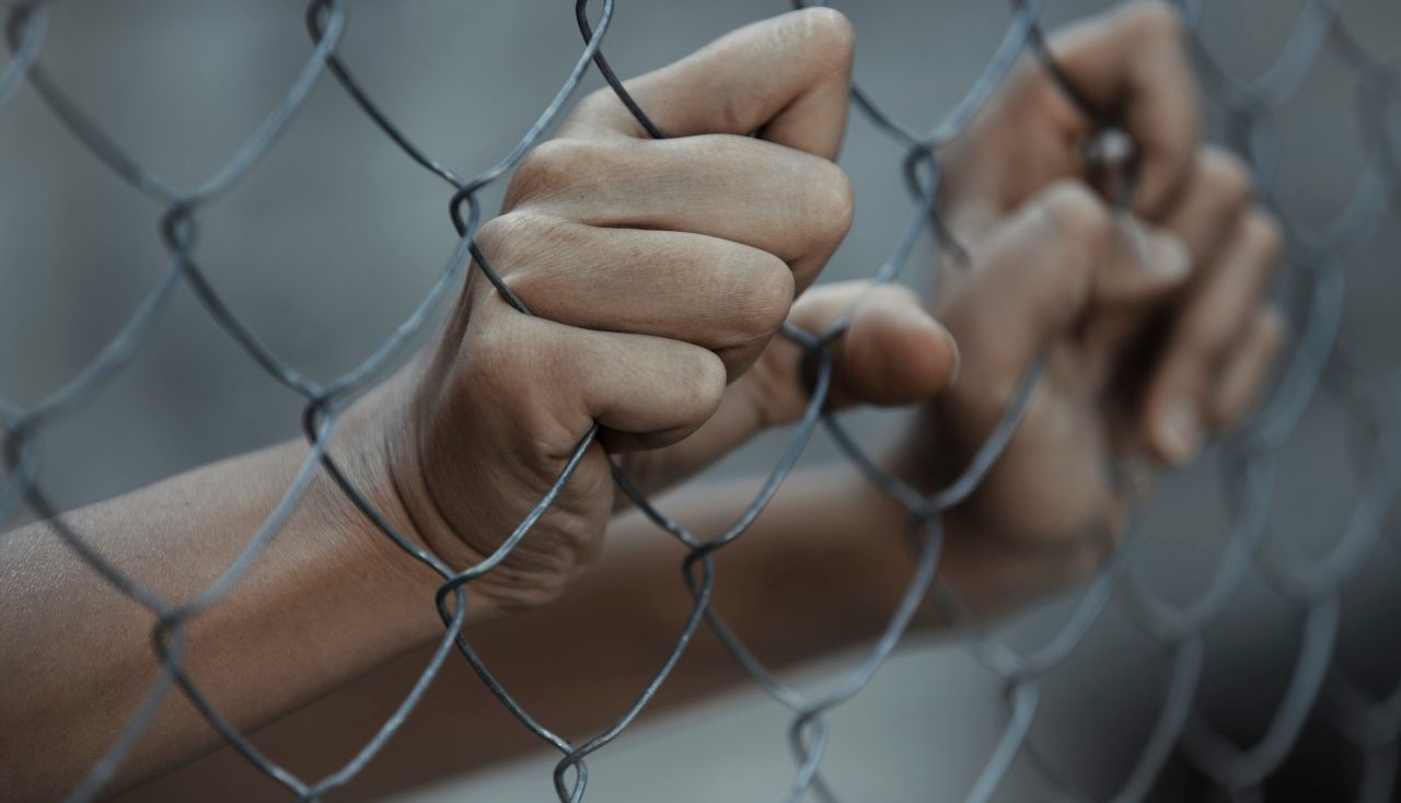 07 Sep 2014 --- Hands of prisoner behind chain link fence --- Image by © Arman Zhenikeyev/Corbis