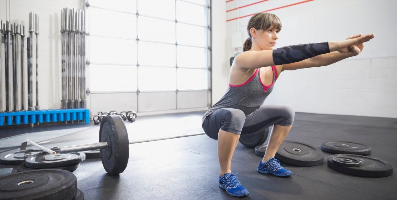 20 Nov 2013, Calgary, Alberta, Canada --- Woman warming up with squats in gym --- Image by © Hero Images/Corbis