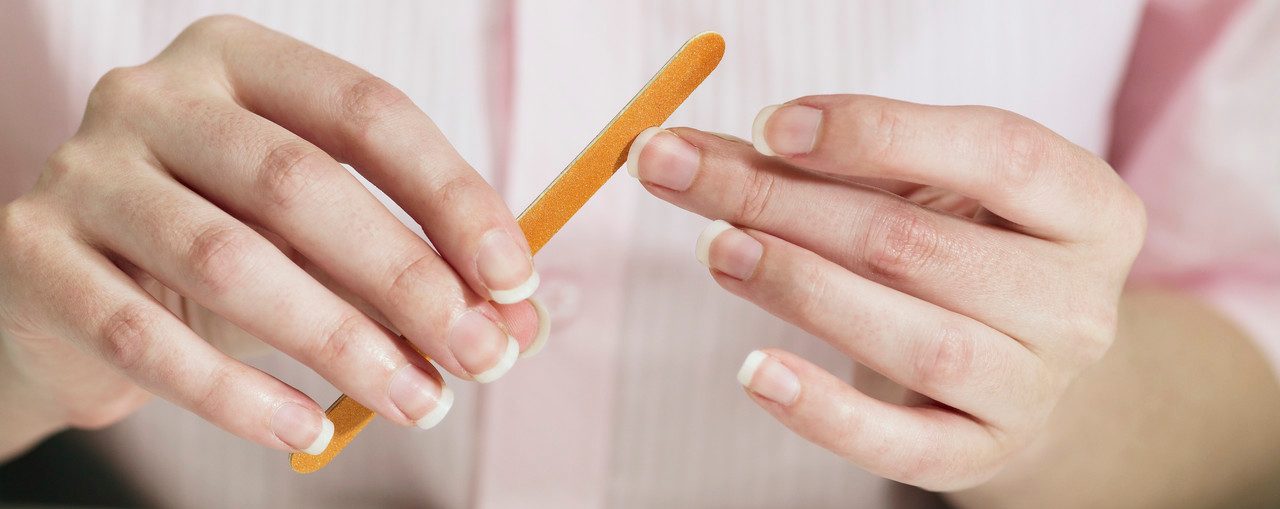 Woman filing her fingernails --- Image by © Mark Weiss/Corbis