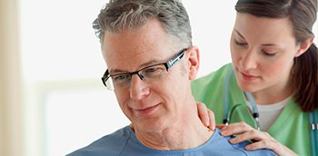 Nurse examining senior male patient.