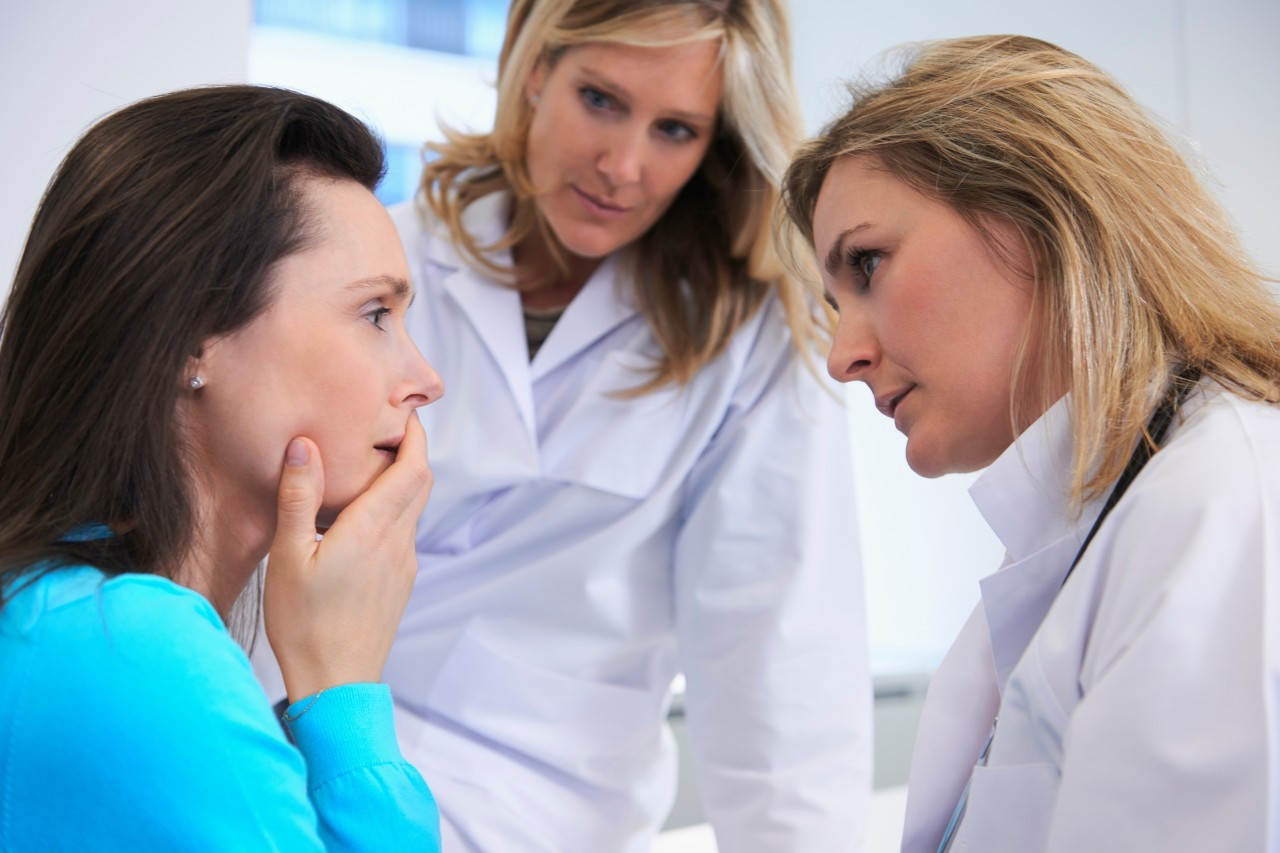 Doctors comforting female patient --- Image by © Ghislain & Marie David de Lossy/Corbis