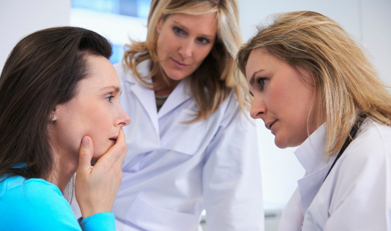 Doctors comforting female patient --- Image by © Ghislain & Marie David de Lossy/Corbis