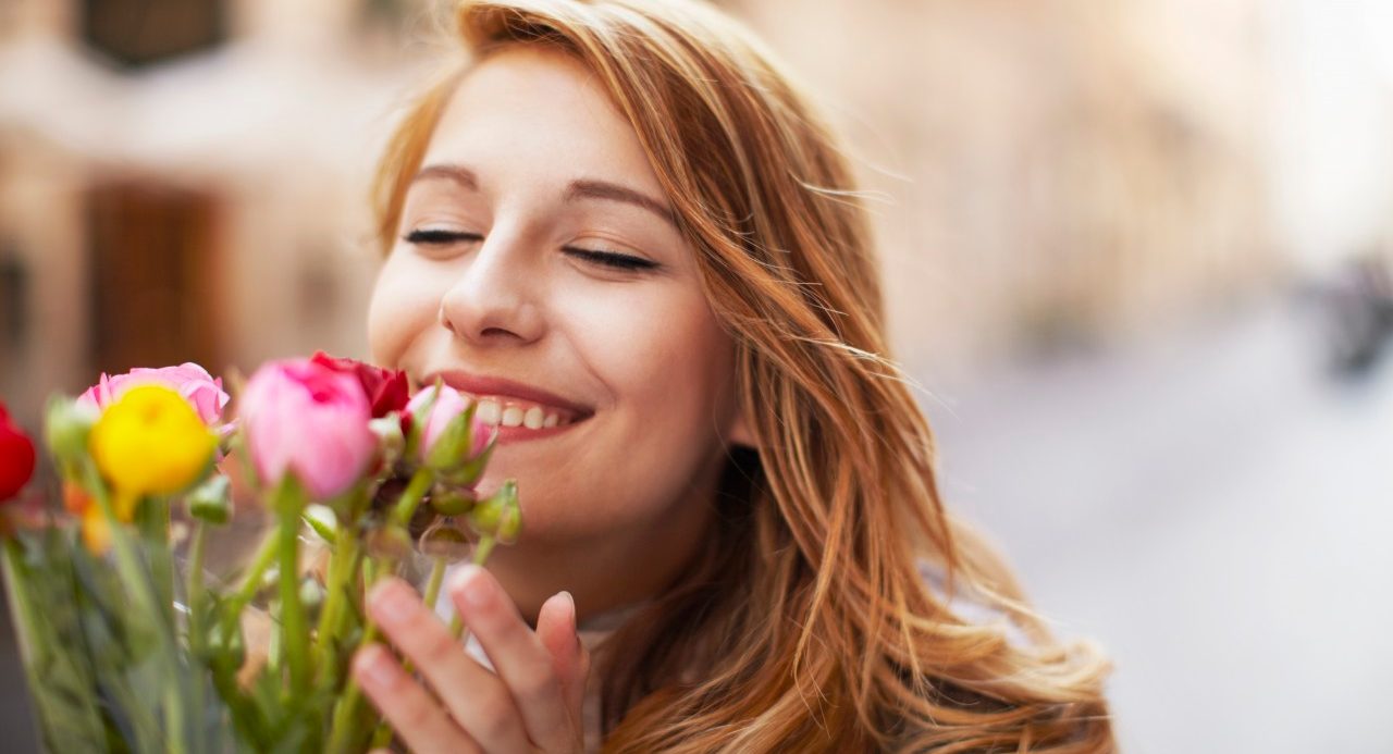 14 Mar 2014 --- Smiling young woman smelling a bunch of flowers --- Image by © Moof/Corbis