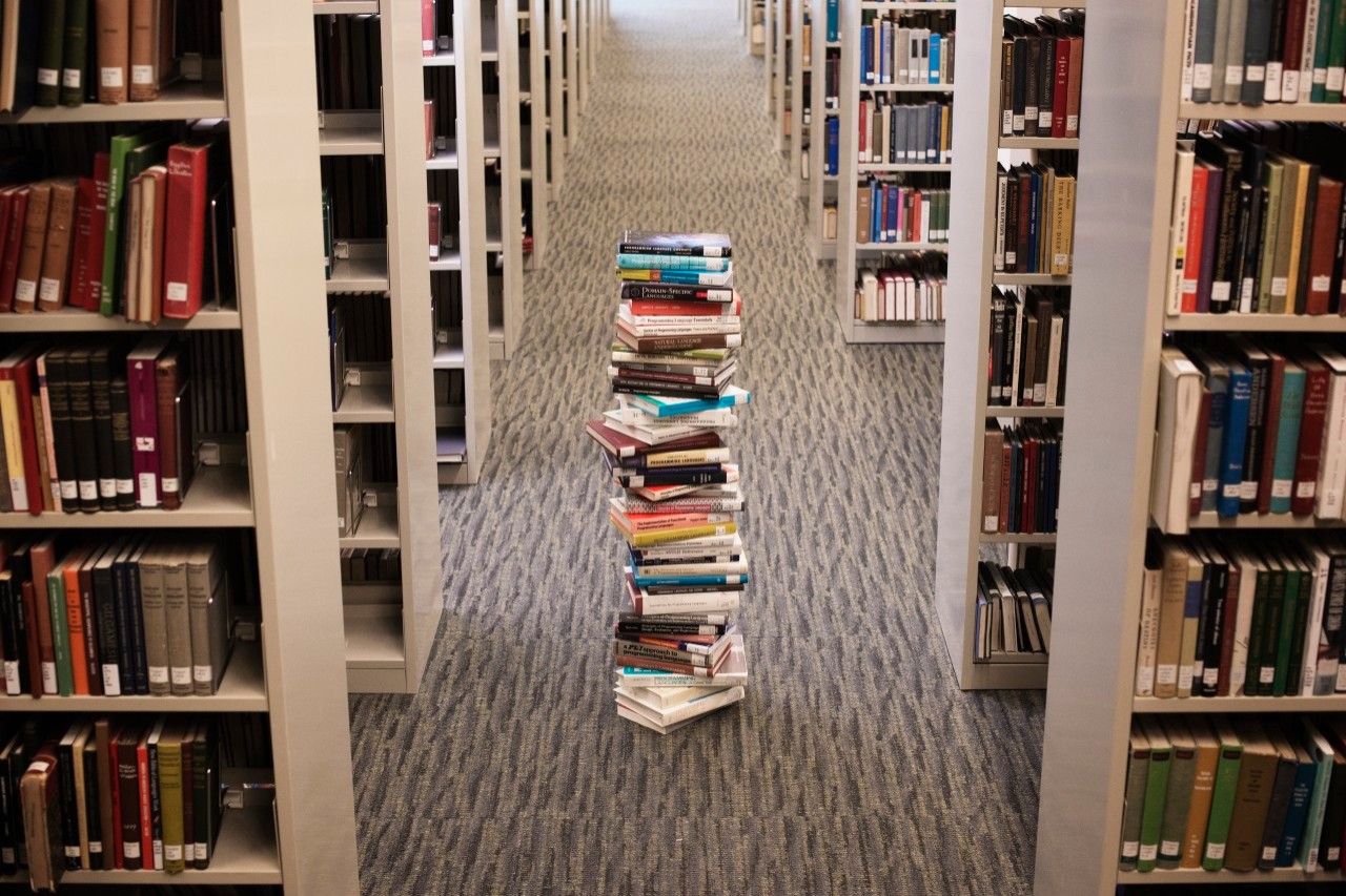 Pile of books standing in library lane --- Image by © Hiya Images/Corbis