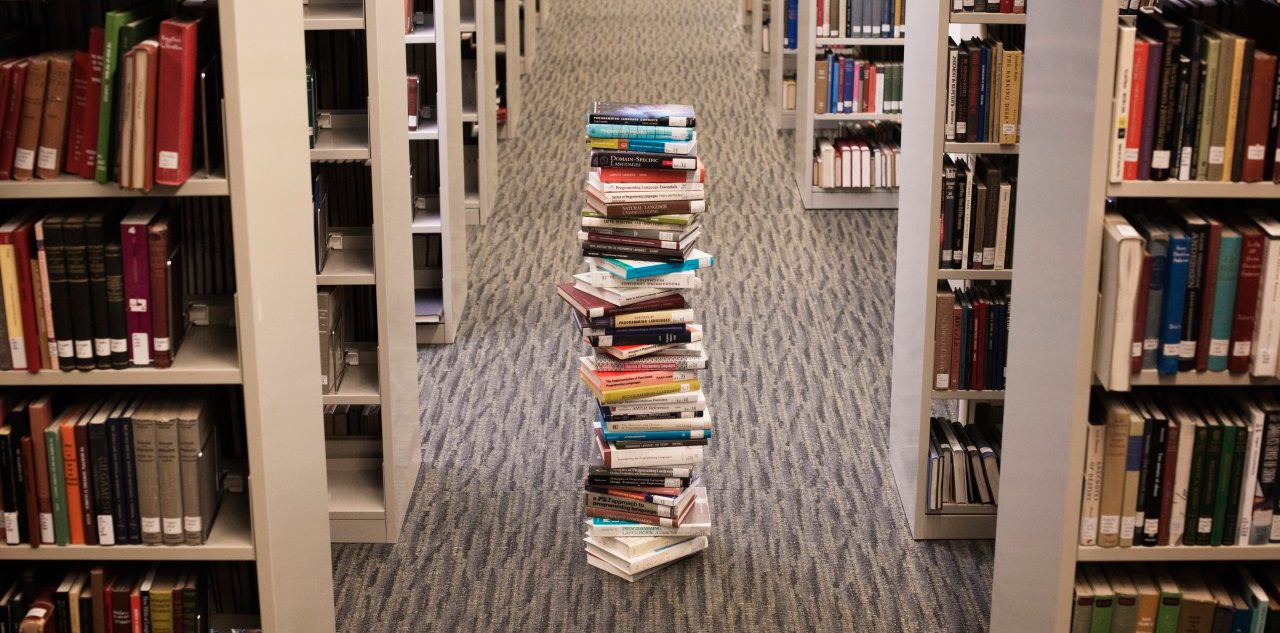 Pile of books standing in library lane --- Image by © Hiya Images/Corbis