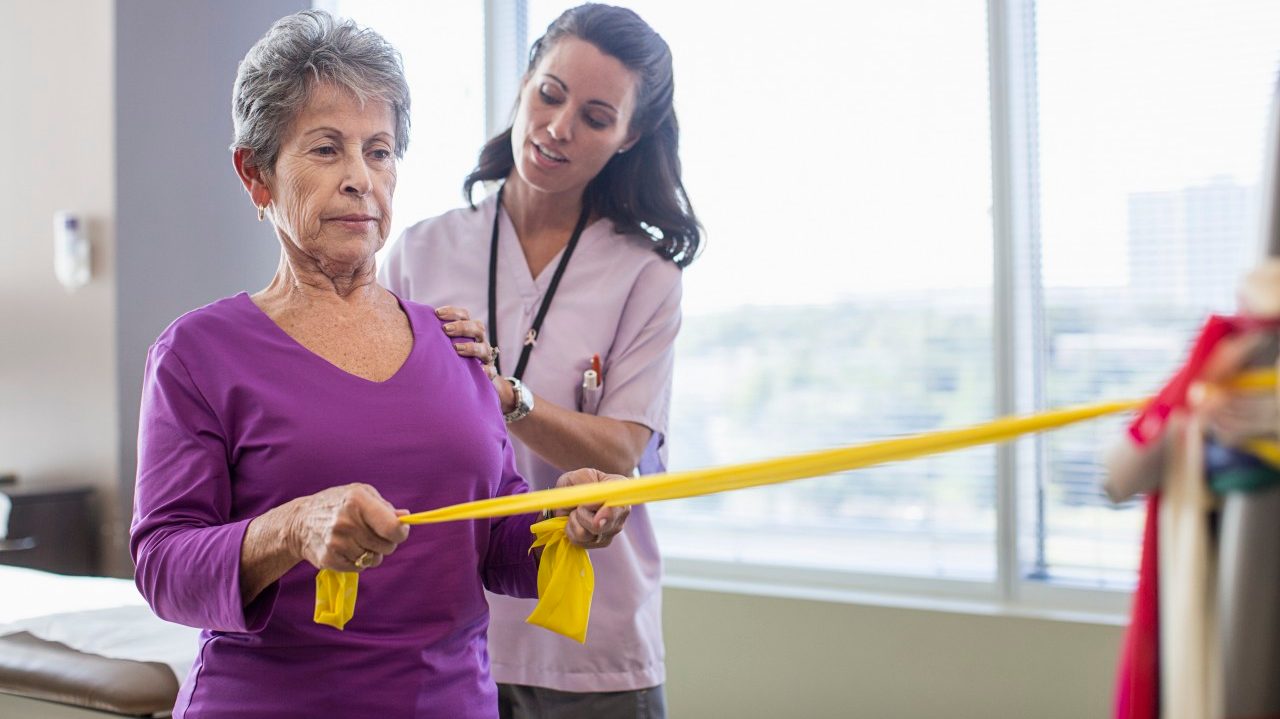 Therapist helping woman in exercises --- Image by © Isaac Lane Koval/Corbis