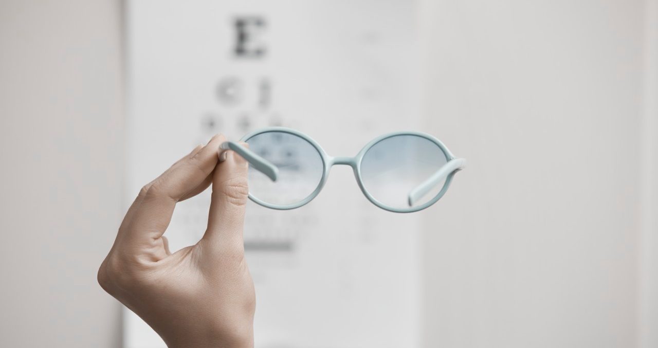 28 Jan 2014 --- Human hand holding eyeglasses near eye test chart --- Image by © Arman Zhenikeyev/Corbis