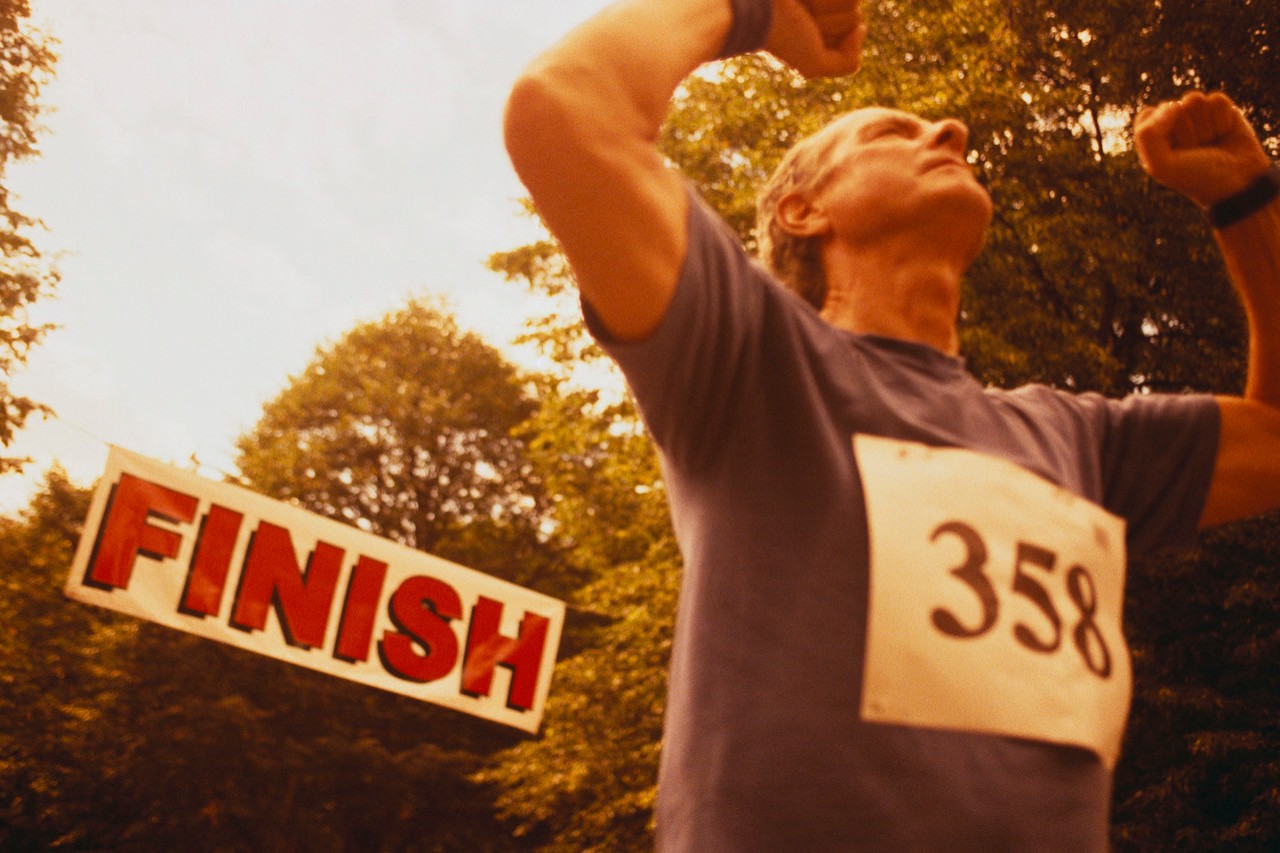 Elderly Runner Crossing Finish Line --- Image by © Dann Tardif/LWA/Corbis